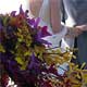 Orchid bouquet in the foreground, Emma and James exchanging rings in background
