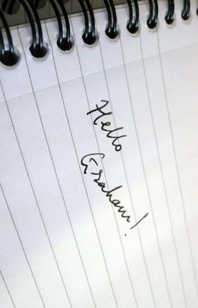 A notepad with 'Hello Graham!' written on it