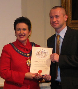 Bryan receives his certificate of citizenship from Clover Moore